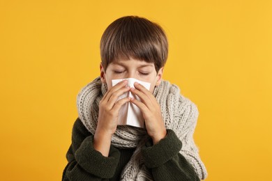 Photo of Cold symptom. Little boy with runny nose on orange background