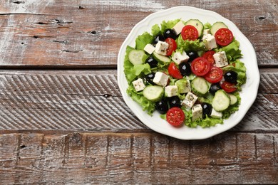 Photo of Delicious salad with feta cheese on wooden table, top view. Space for text