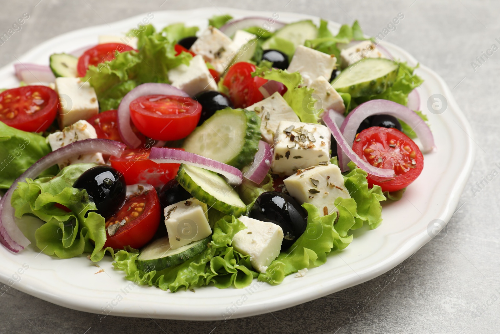 Photo of Delicious salad with feta cheese on gray textured table, closeup