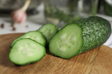 Photo of Wooden board with fresh cut cucumber on table, closeup