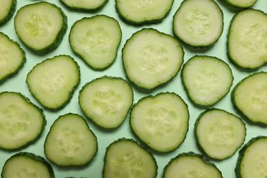 Photo of Slices of fresh cucumbers on turquoise background, flat lay