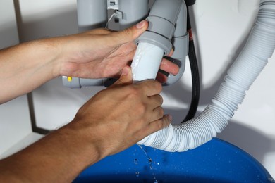 Photo of Professional plumber fixing piping system at home, closeup