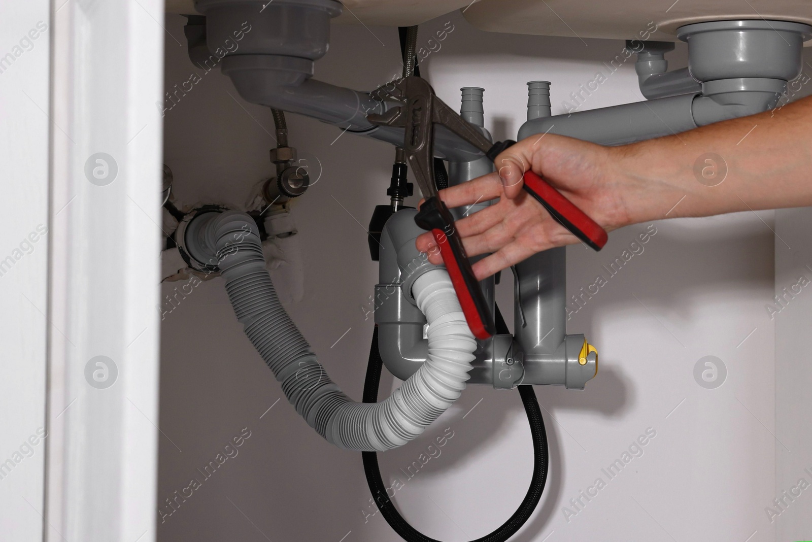 Photo of Professional plumber fixing piping system at home, closeup