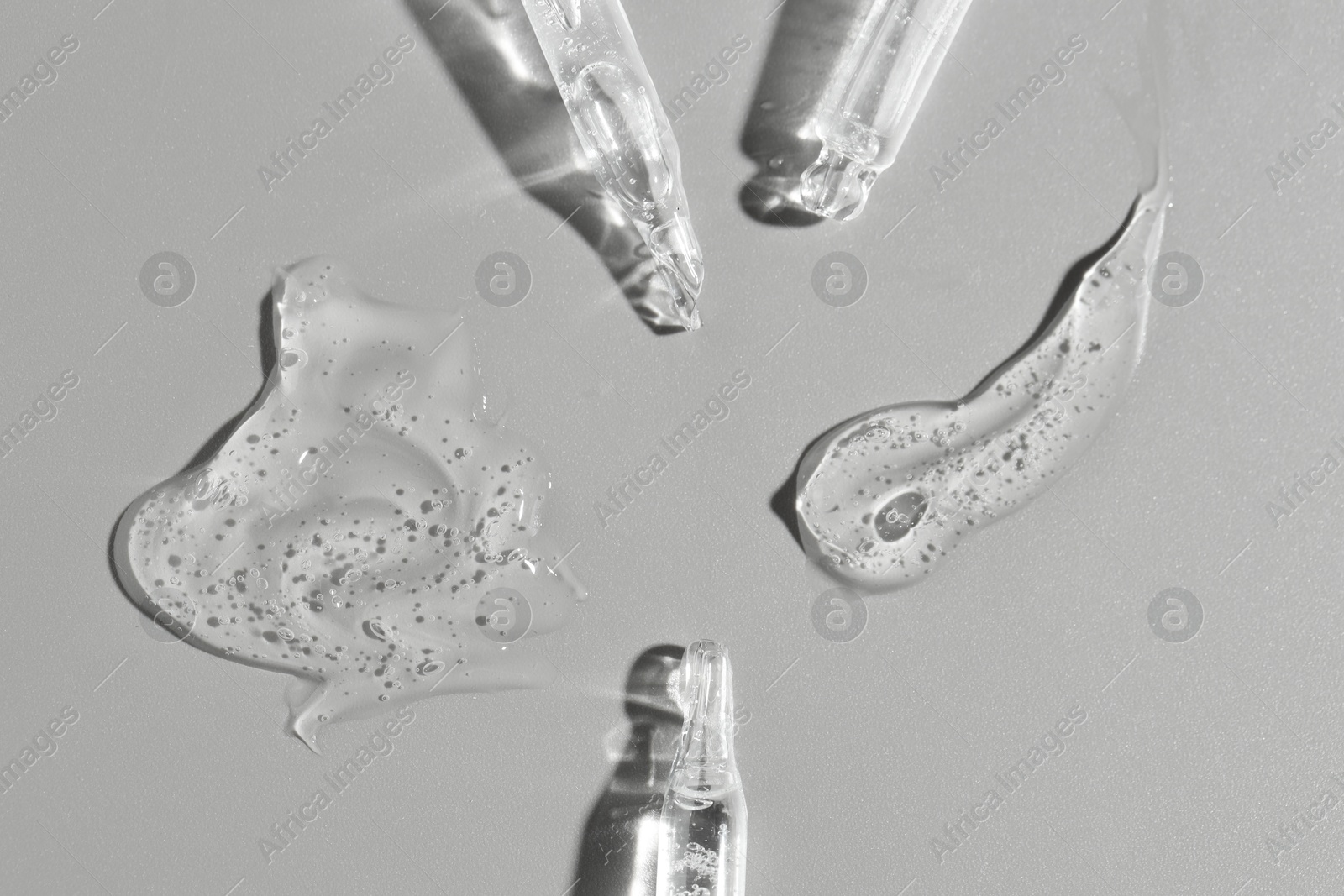 Photo of Cosmetic serum and pipettes on grey background, flat lay