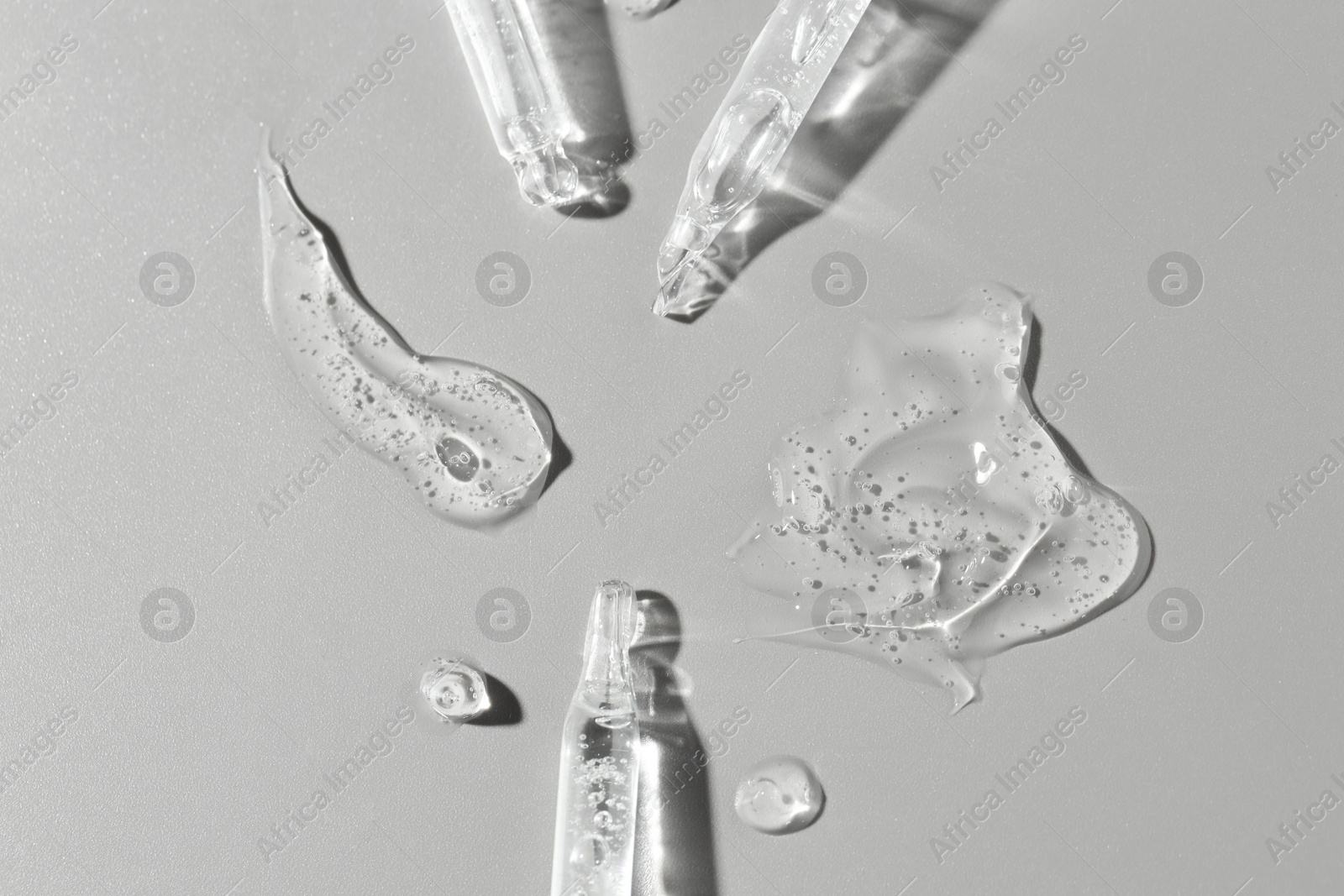 Photo of Cosmetic serum and pipettes on grey background, flat lay