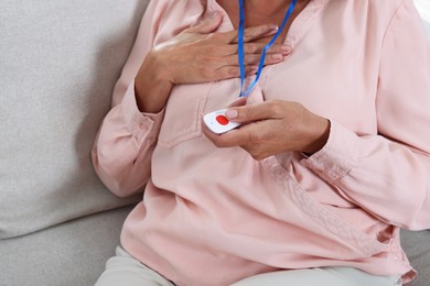 Senior woman pressing emergency call button at home, closeup