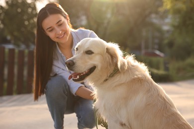 Photo of Happy owner with cute Golden Retriever dog outdoors on sunny day