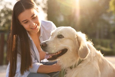 Photo of Happy owner with cute Golden Retriever dog outdoors on sunny day