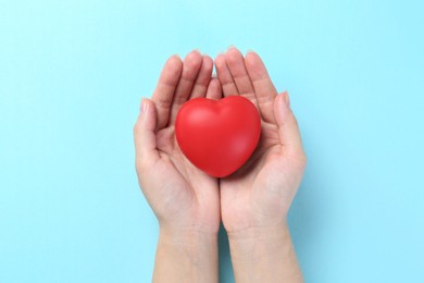 Photo of Woman with red heart on light blue background, top view