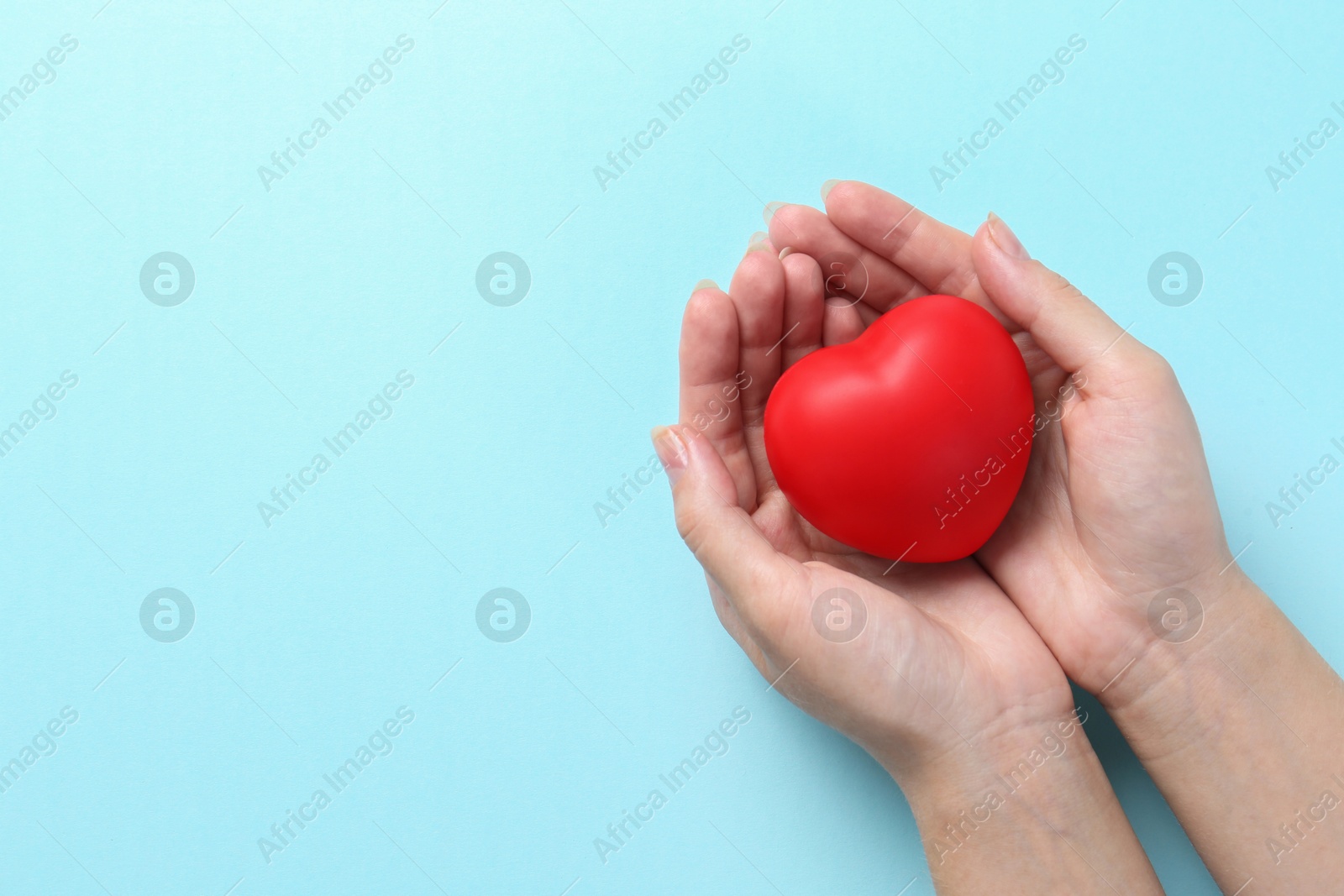 Photo of Woman with red heart on light blue background, top view. Space for text