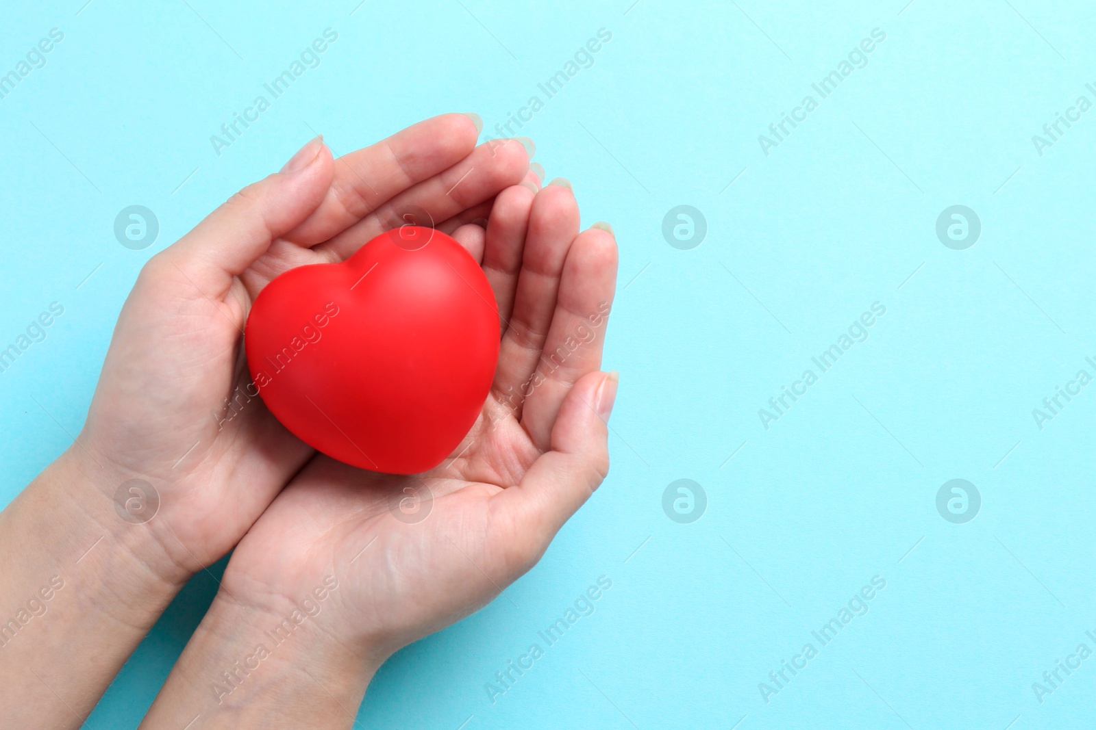 Photo of Woman with red heart on light blue background, top view. Space for text