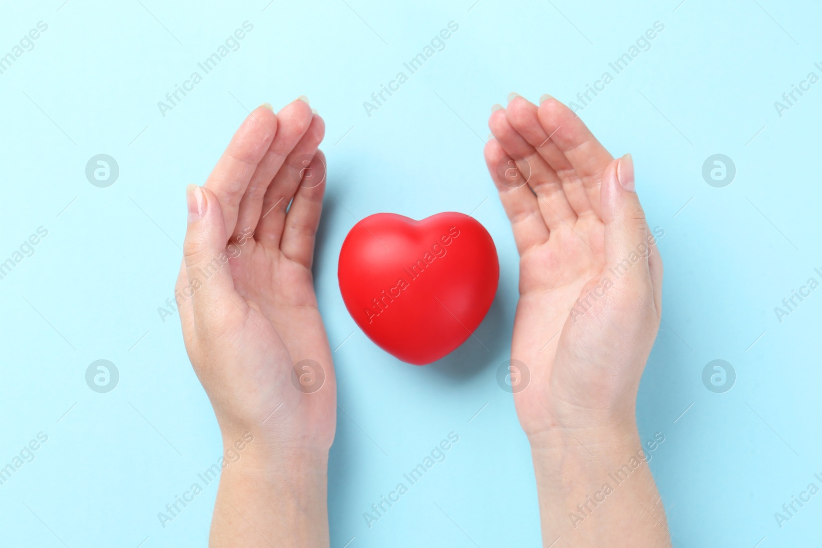 Photo of Woman with red heart on light blue background, top view