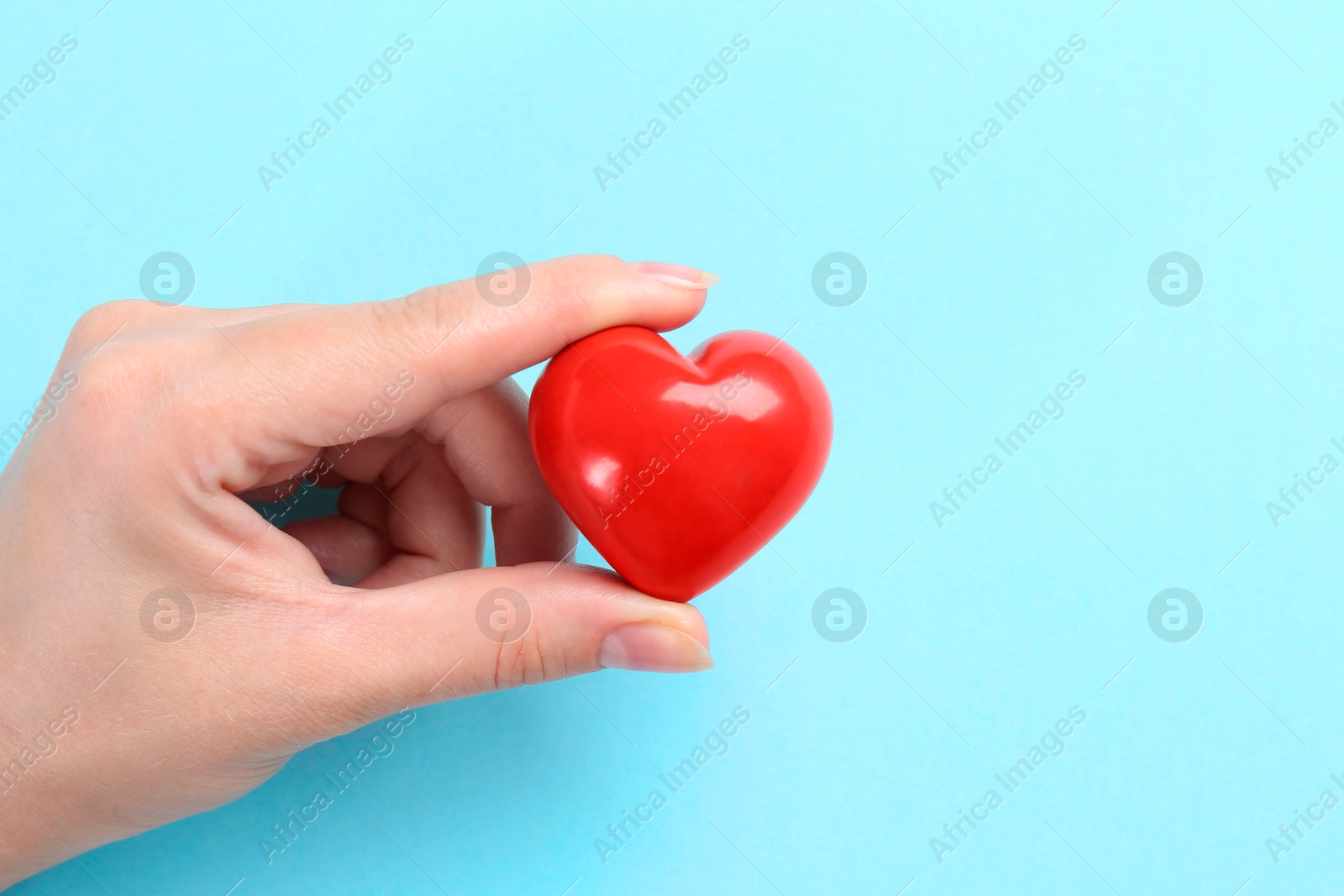 Photo of Woman with red heart on light blue background, closeup