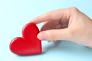 Photo of Woman with red heart on light blue background, closeup