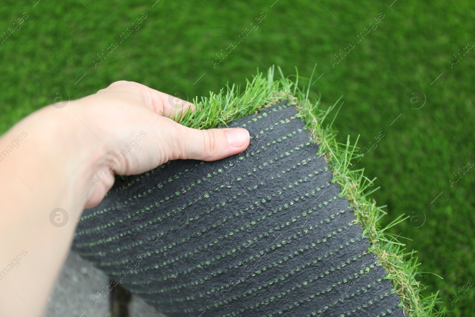 Photo of Woman with sheet of artificial turf, closeup