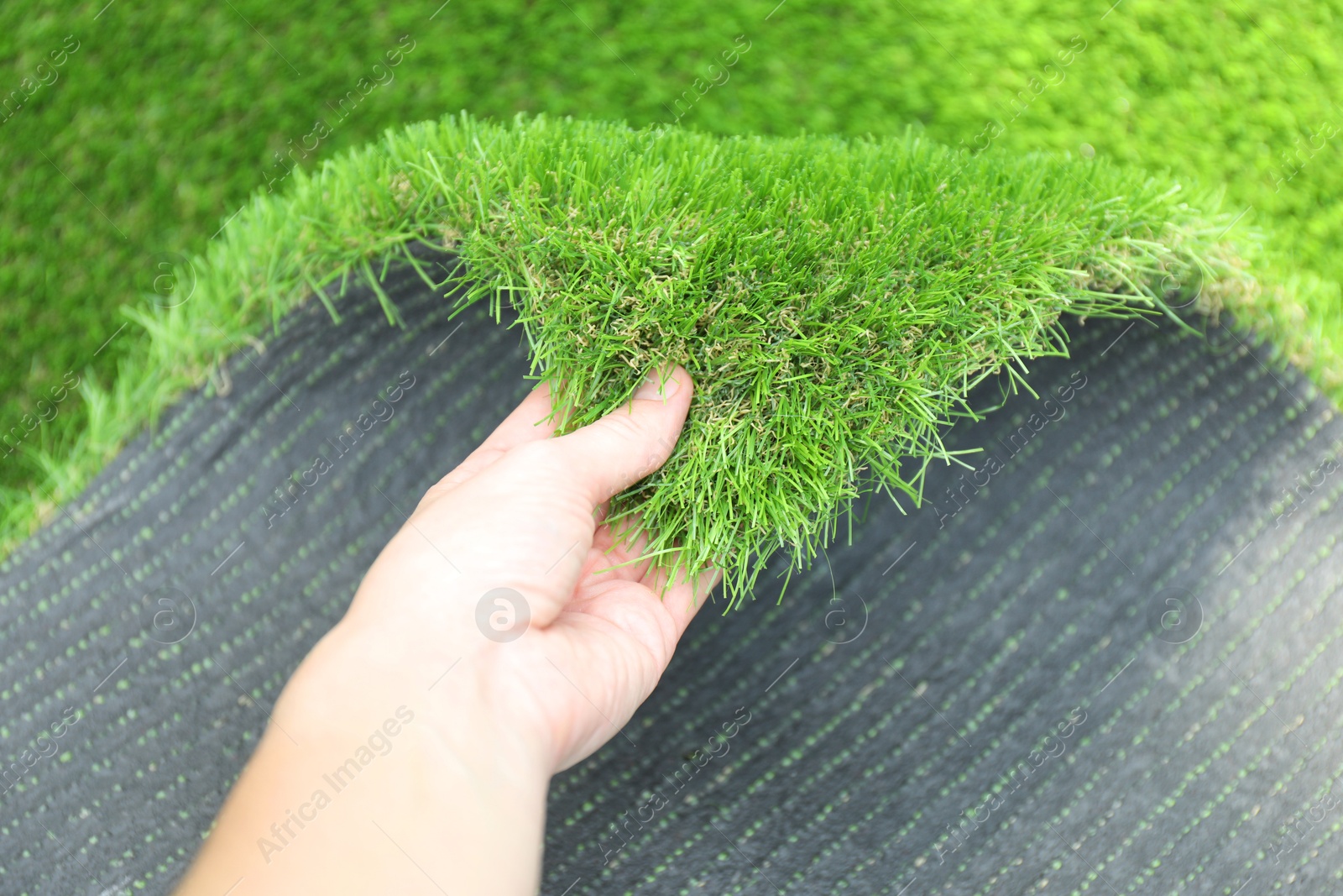 Photo of Woman with sheet of artificial turf, closeup