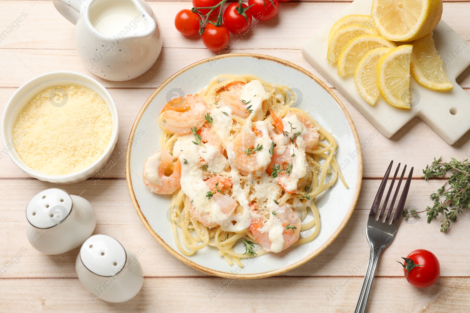 Photo of Tasty pasta with shrimps, creamy sauce and cheese on light wooden table, flat lay