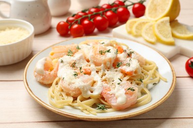 Tasty pasta with shrimps, creamy sauce and cheese served on light wooden table, closeup