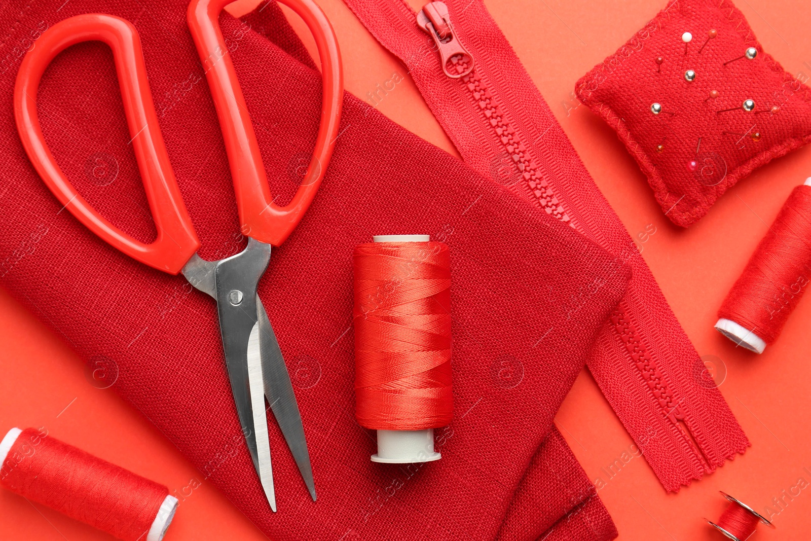 Photo of Flat lay composition with different sewing supplies on coral background