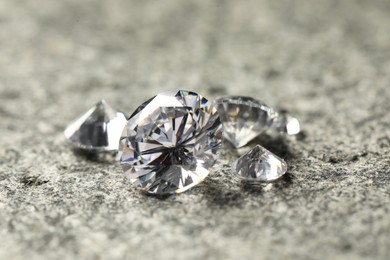 Many beautiful shiny diamonds on grey table, closeup