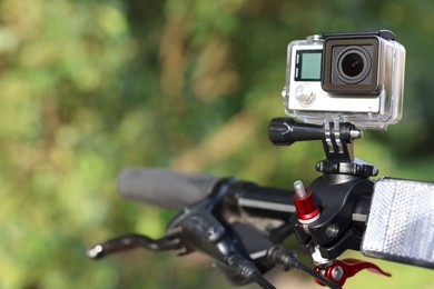 Modern action camera with mount on bicycle outdoors, space for text