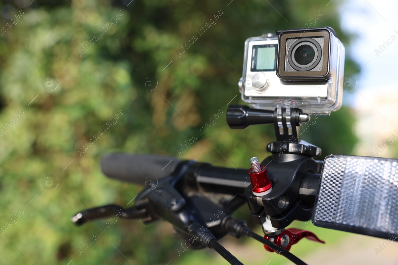 Photo of Modern action camera with mount on bicycle outdoors, space for text