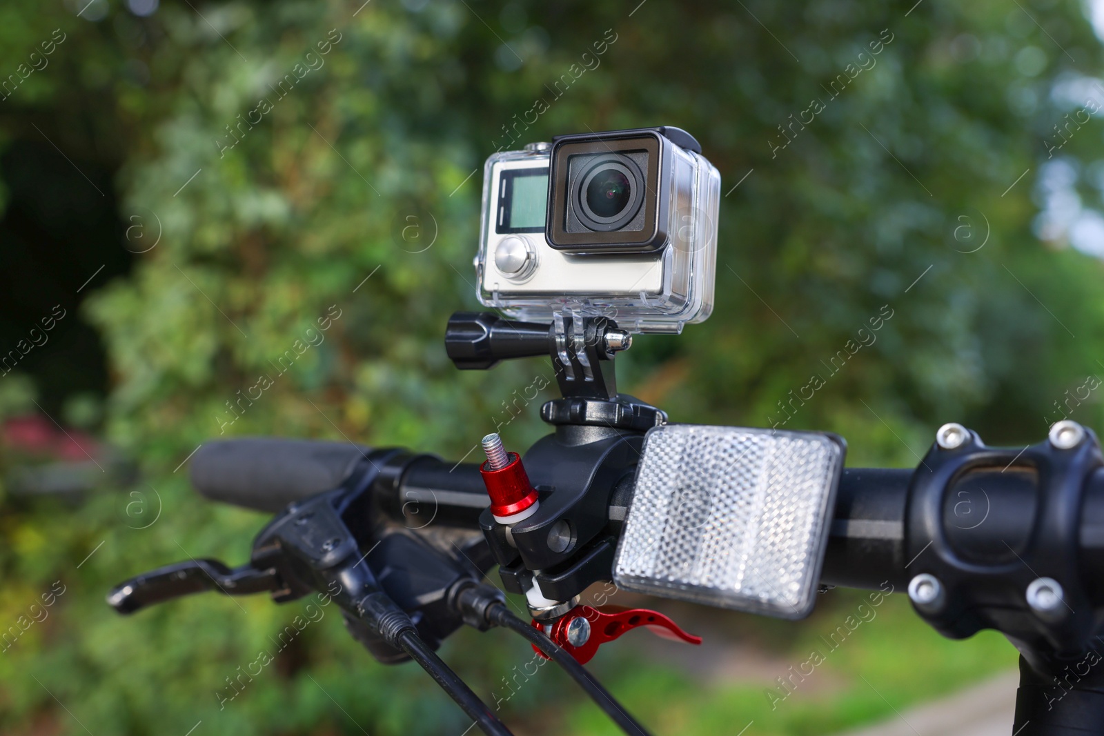 Photo of Modern action camera with mount on bicycle outdoors, closeup