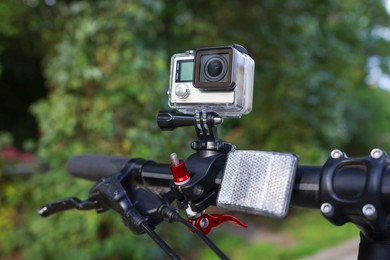 Photo of Modern action camera with mount on bicycle outdoors, closeup