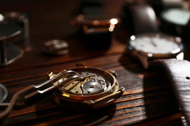 Photo of Mechanism of vintage wrist watch and tool on wooden table, closeup