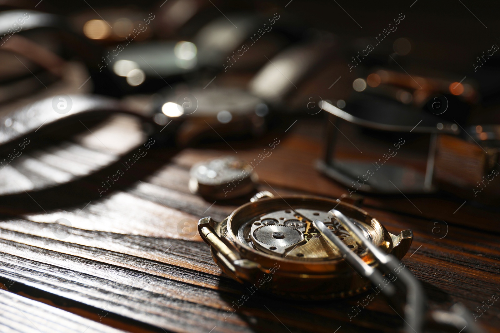 Photo of Mechanism of vintage wrist watch and tool on wooden table, closeup