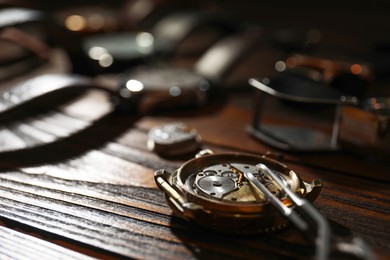 Photo of Mechanism of vintage wrist watch and tool on wooden table, closeup