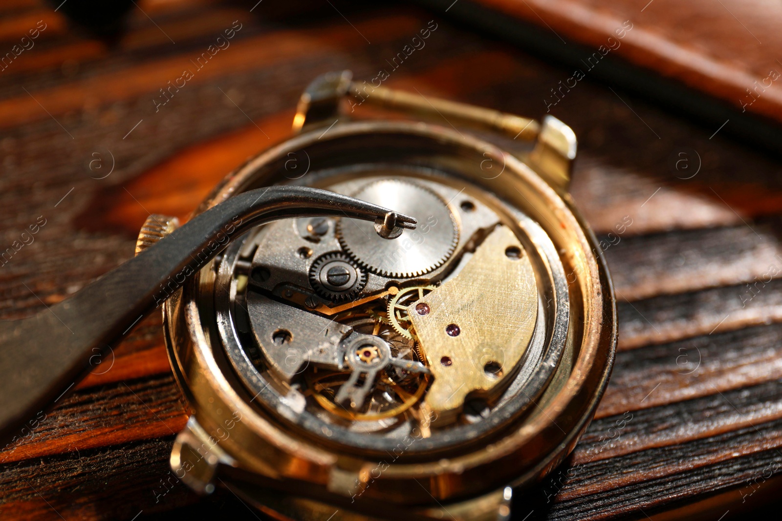 Photo of Mechanism of vintage wrist watch and tool on wooden table, closeup