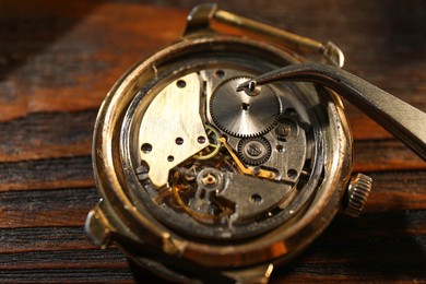 Photo of Mechanism of vintage wrist watch and tool on wooden table, closeup