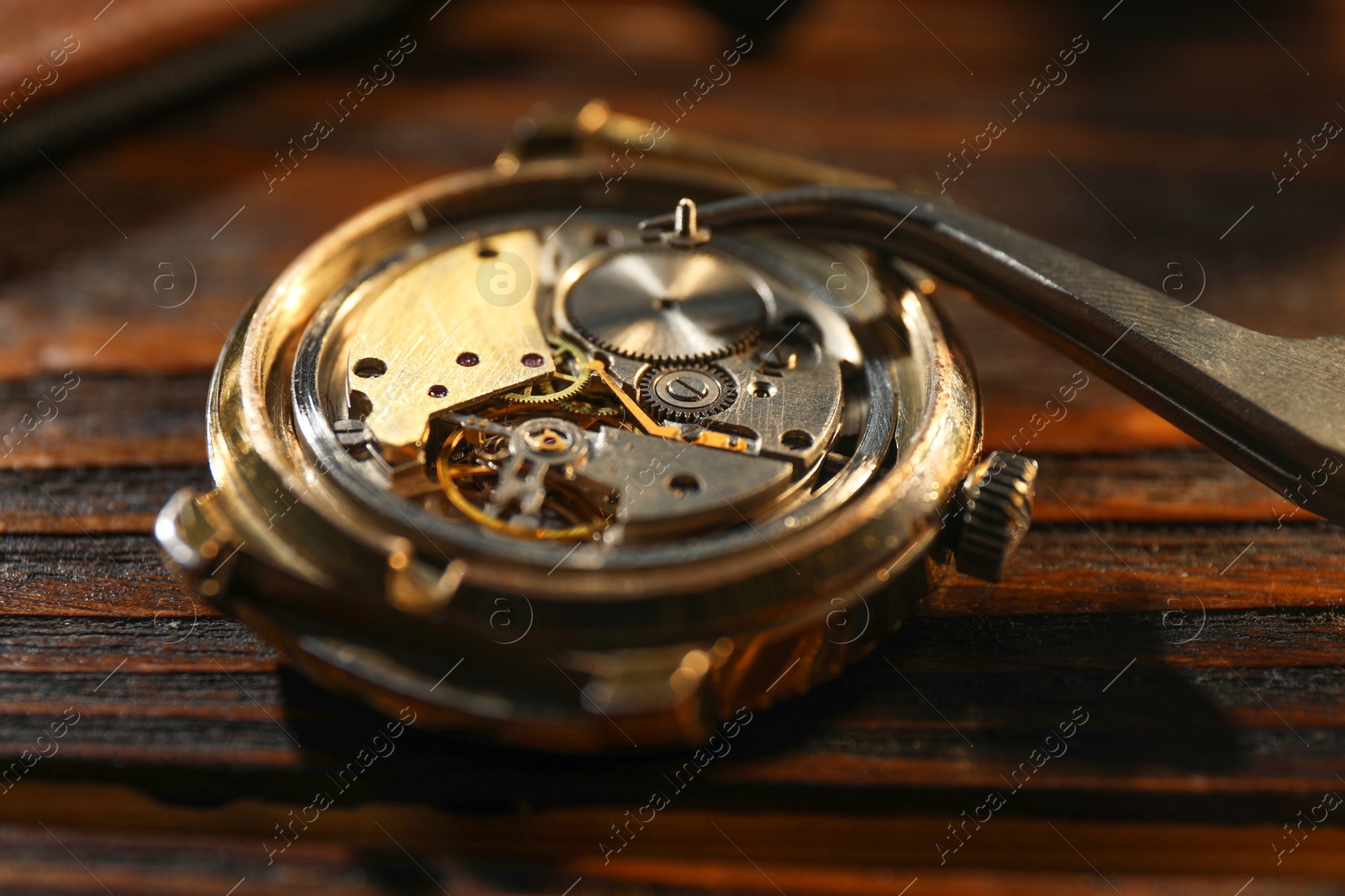 Photo of Mechanism of vintage wrist watch and tool on wooden table, closeup