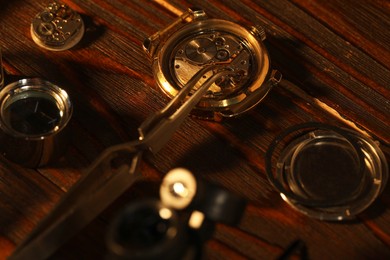 Photo of Mechanism of vintage wrist watch and tool on wooden table, closeup