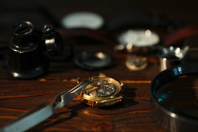 Photo of Mechanism of vintage wrist watch and tool on wooden table, closeup