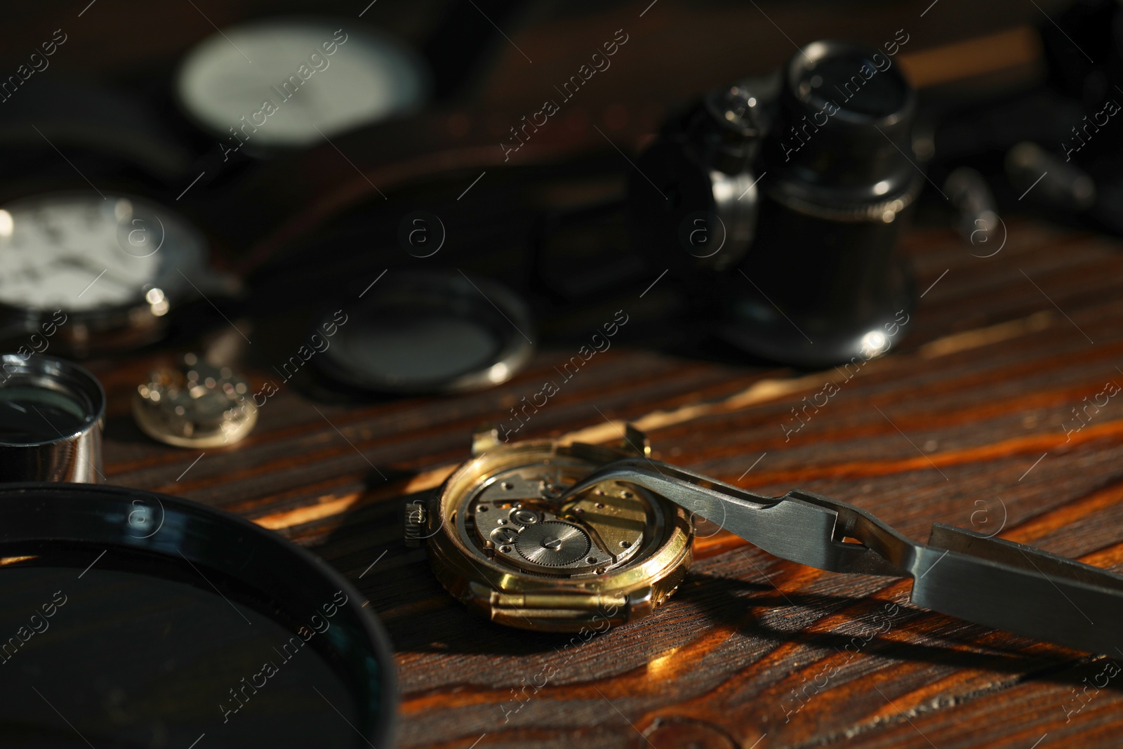 Photo of Mechanism of vintage wrist watch and tool on wooden table, closeup