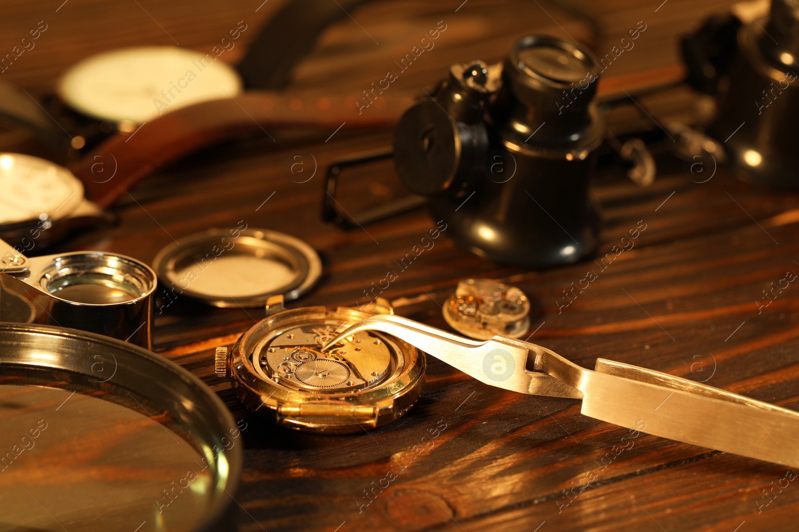 Photo of Mechanism of vintage wrist watch and tool on wooden table, closeup