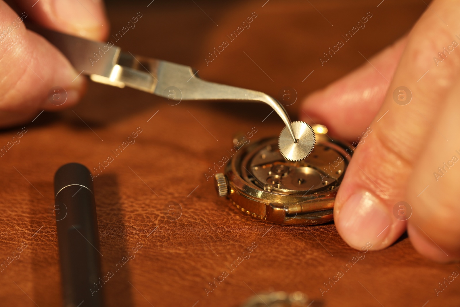 Photo of Man fixing mechanism of vintage wrist watch at table, closeup