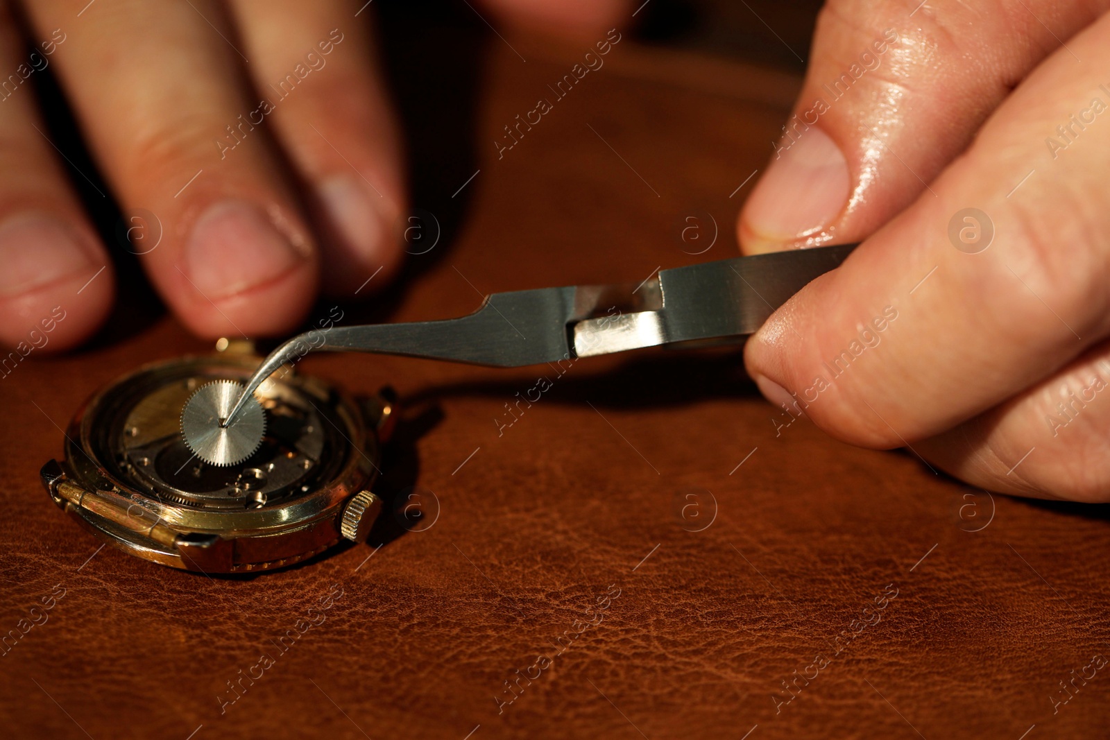 Photo of Man fixing mechanism of vintage wrist watch at table, closeup