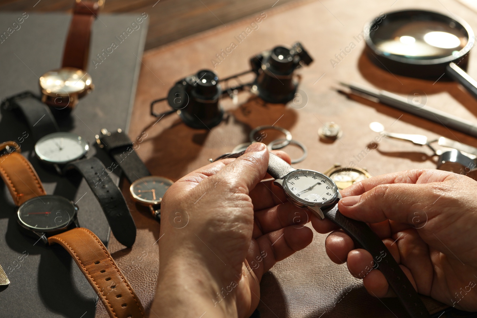 Photo of Clock mechanism. Man with vintage wrist watch at table, closeup