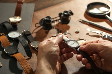 Photo of Clock mechanism. Man with vintage wrist watch at table, closeup