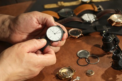 Photo of Clock mechanism. Man with vintage wrist watch at table, closeup