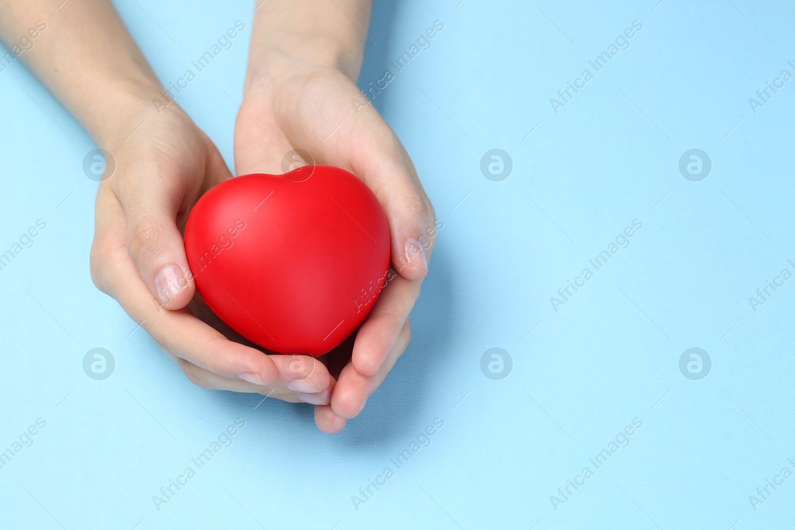 Photo of Woman holding red heart on light blue background, closeup. Space for text