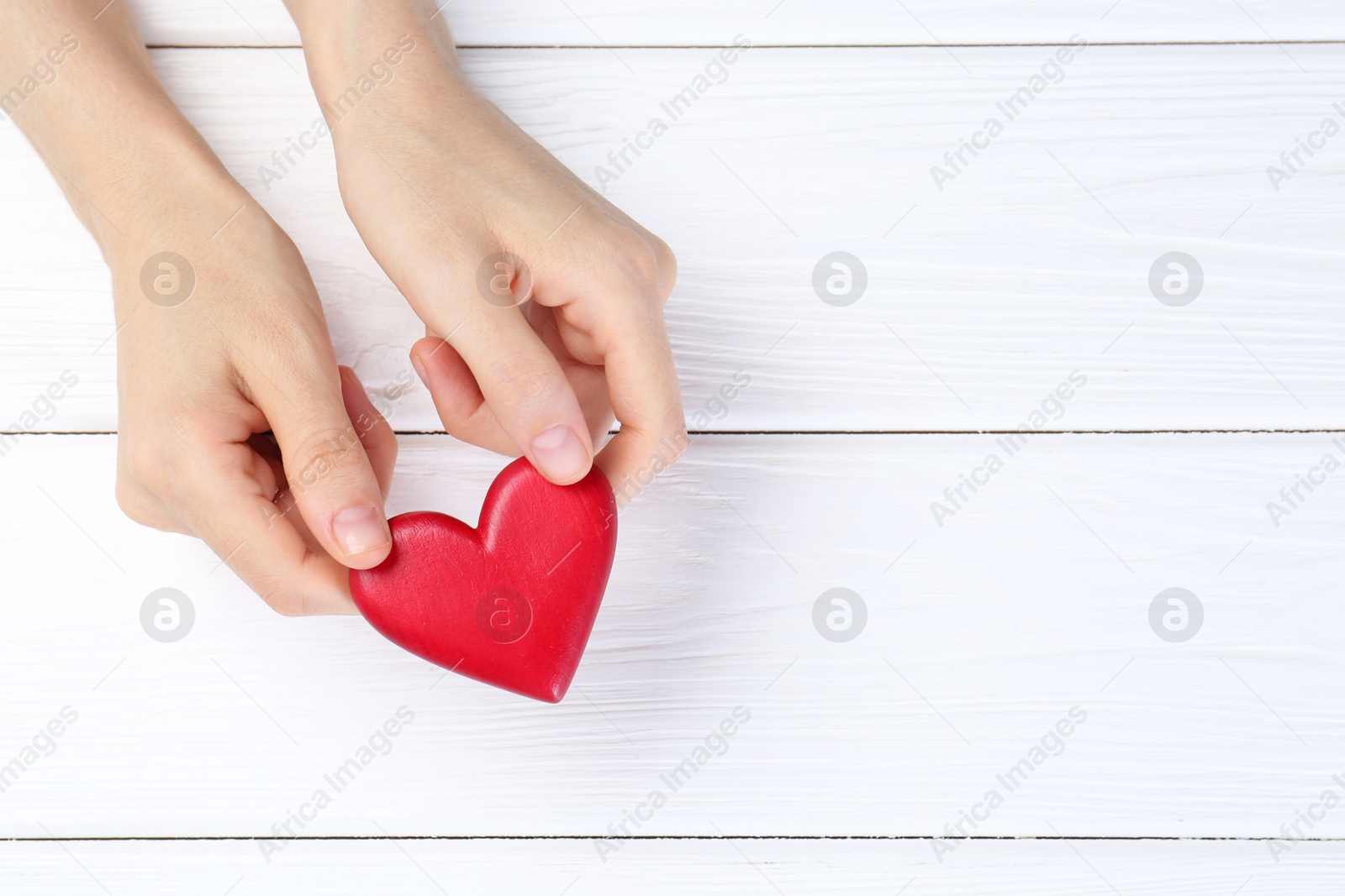 Photo of Woman holding red heart on white wooden background, top view. Space for text