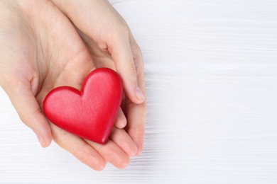 Photo of Woman holding red heart on white wooden background, top view. Space for text