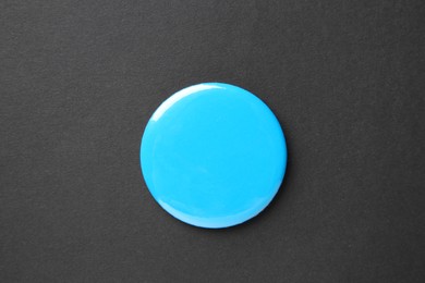 Photo of Blank light blue button badge on black background, top view. Mockup for design