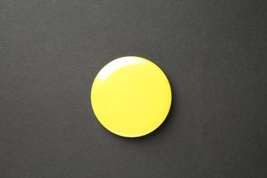 Photo of Blank yellow button badge on black background, top view. Mockup for design