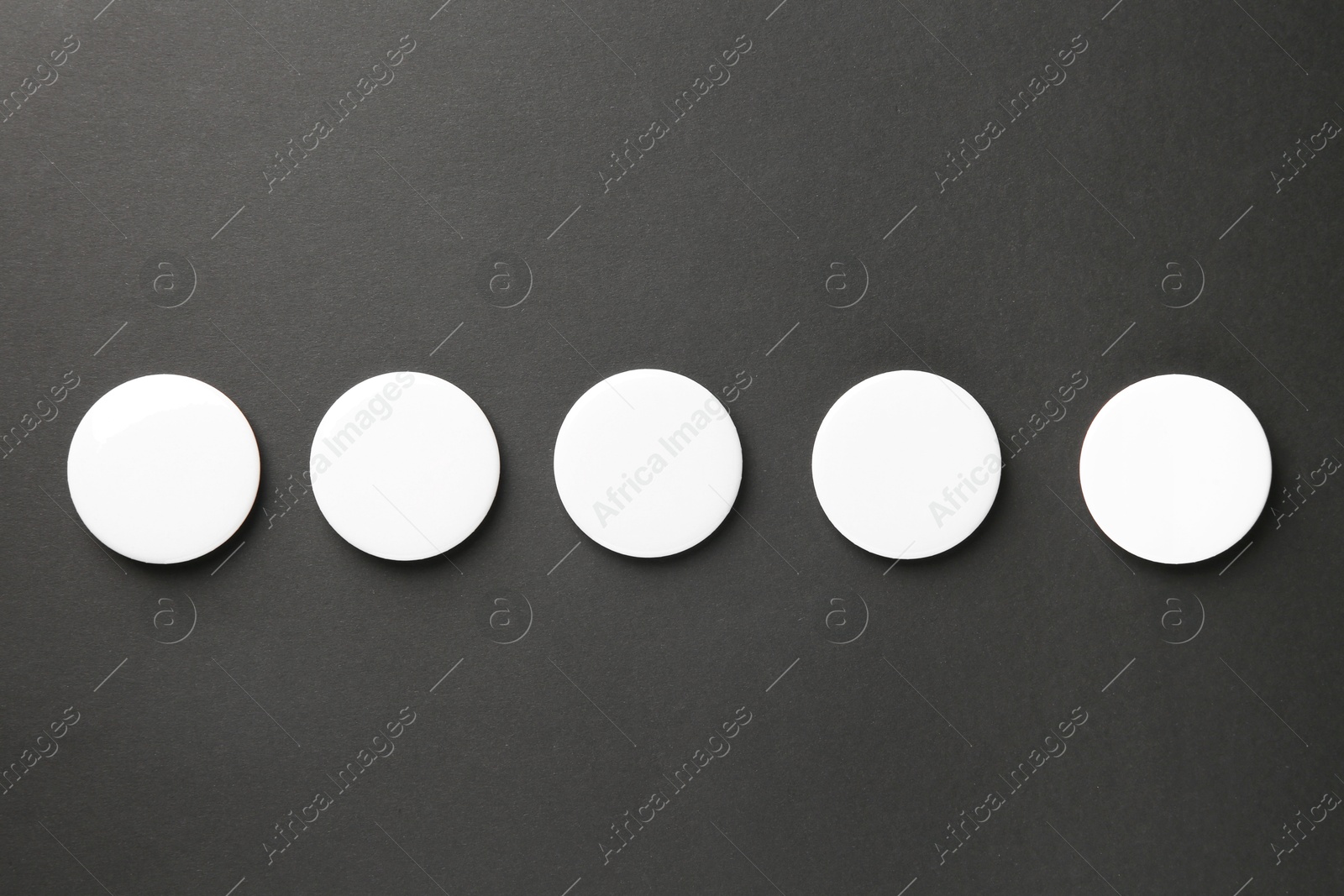 Photo of Blank white button badges on black background, top view. Mockup for design