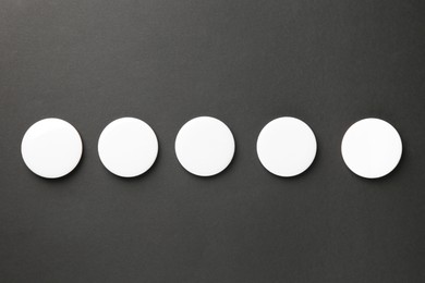 Photo of Blank white button badges on black background, top view. Mockup for design